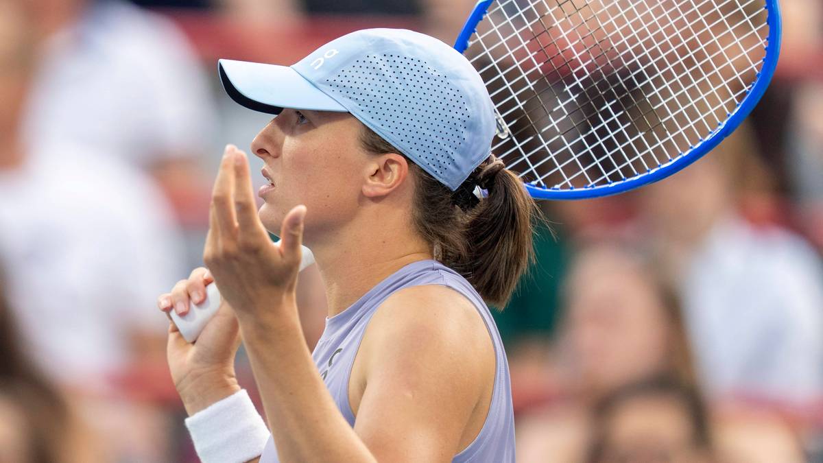 Iga Świątek w jasnoniebieskiej czapce i stroju tenisowym, trzymająca rakietę tenisową.