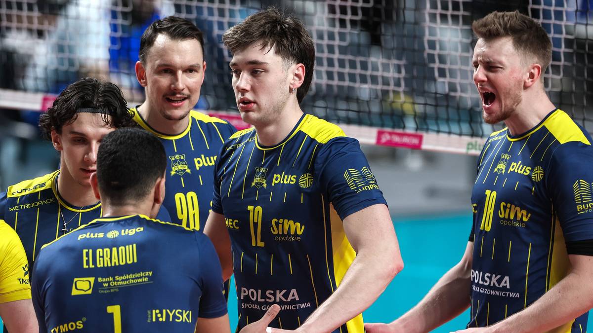 Grupa siatkarzy w niebiesko-żółtych strojach patrzy w tym samym kierunku, dyskutując lub planując strategię.