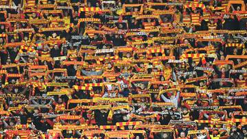 Tłum kibiców Jagiellonii Białystok trzymających szaliki w barwach klubu.