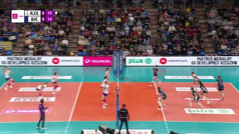 Dwie drużyny siatkarskie grają mecz na boisku, widoczny wynik na tablicy.