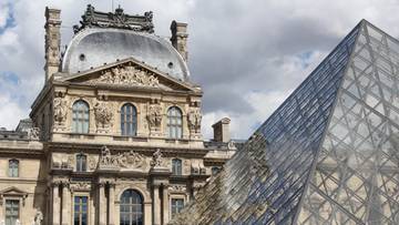 Widok na fasadę Luwru z charakterystyczną szklaną piramidą przed wejściem.