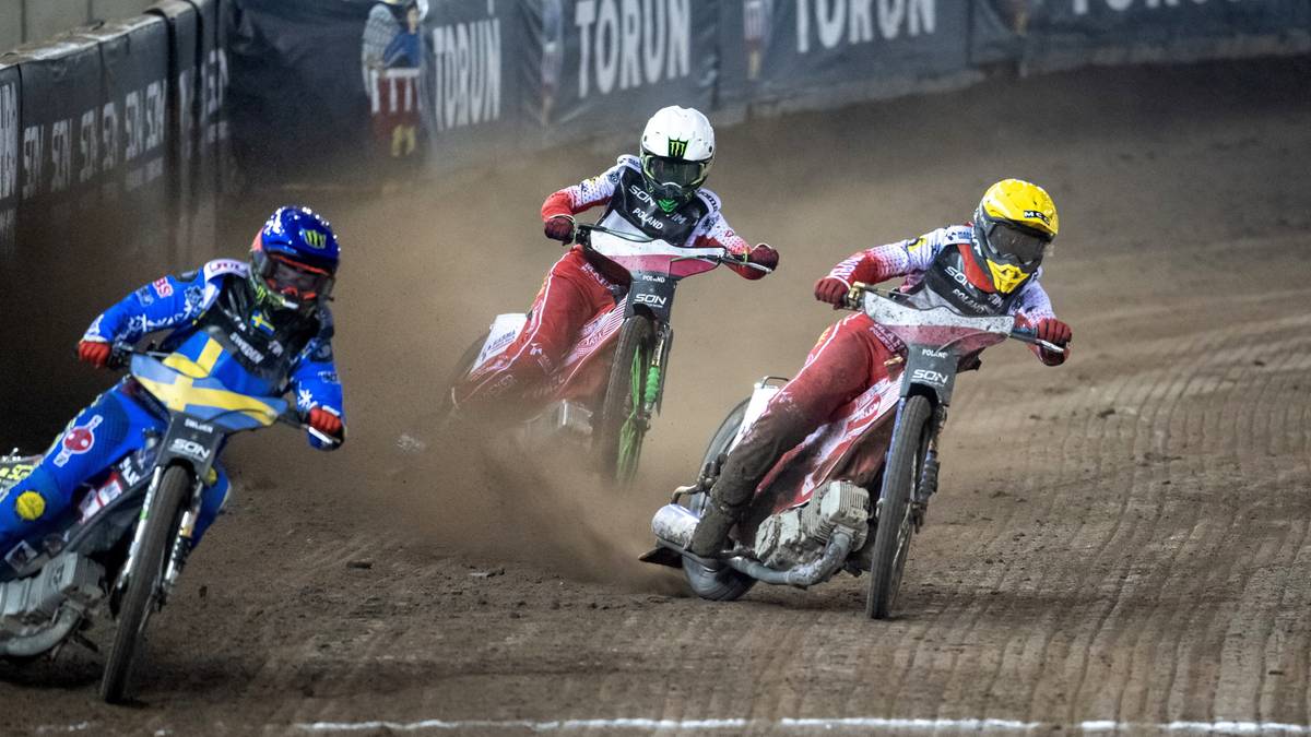 Trzech zawodników żużlowych w kaskach ściga się na torze.