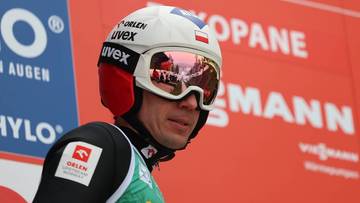 Skoczek narciarski w kasku i goglach, z widocznymi odbiciami w soczewkach.