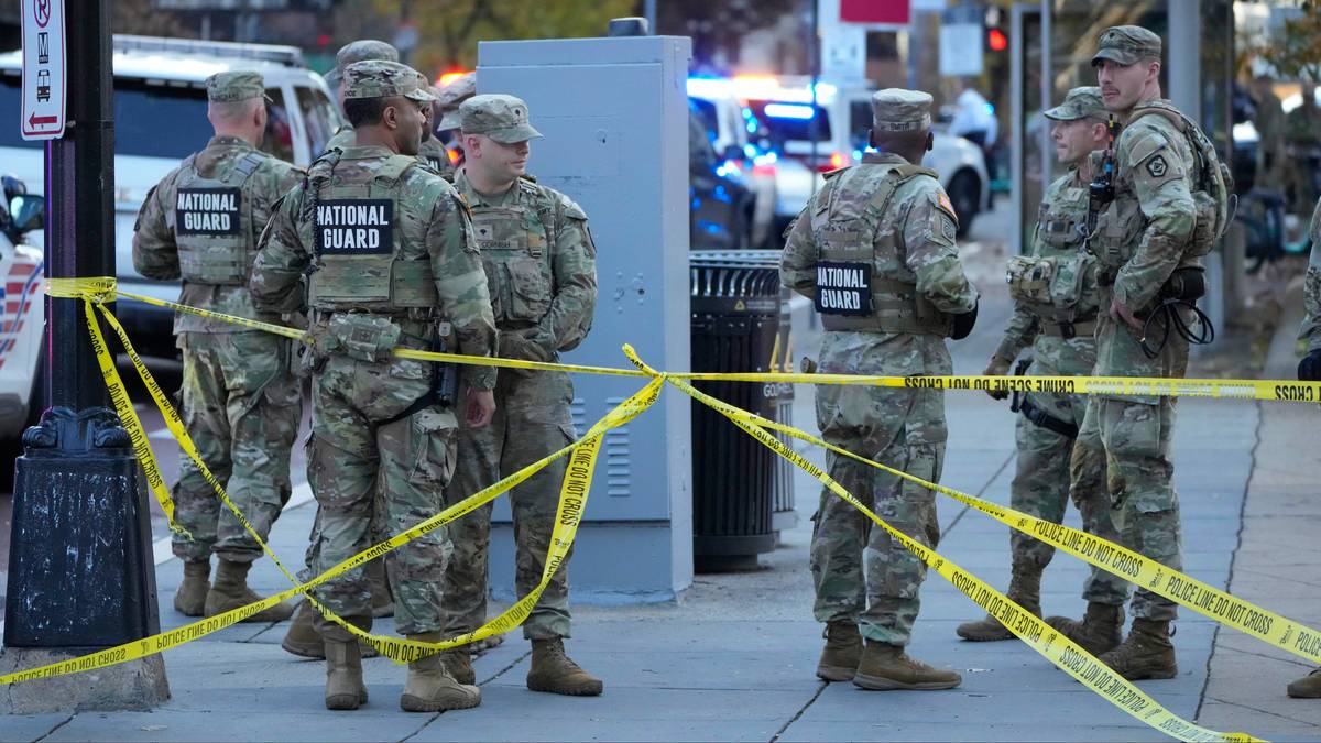 Grupa żołnierzy Gwardii Narodowej w mundurach stoi za żółtą taśmą policyjną.