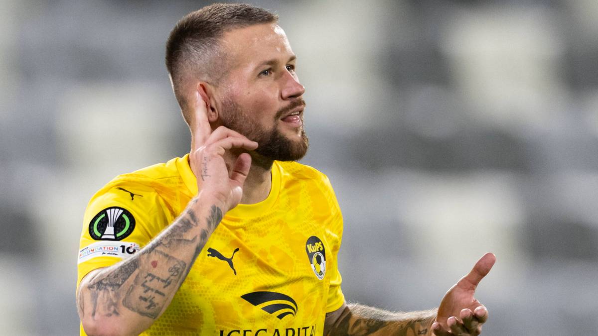 Piłkarz w żółtej koszulce KuPS gestykuluje na boisku.