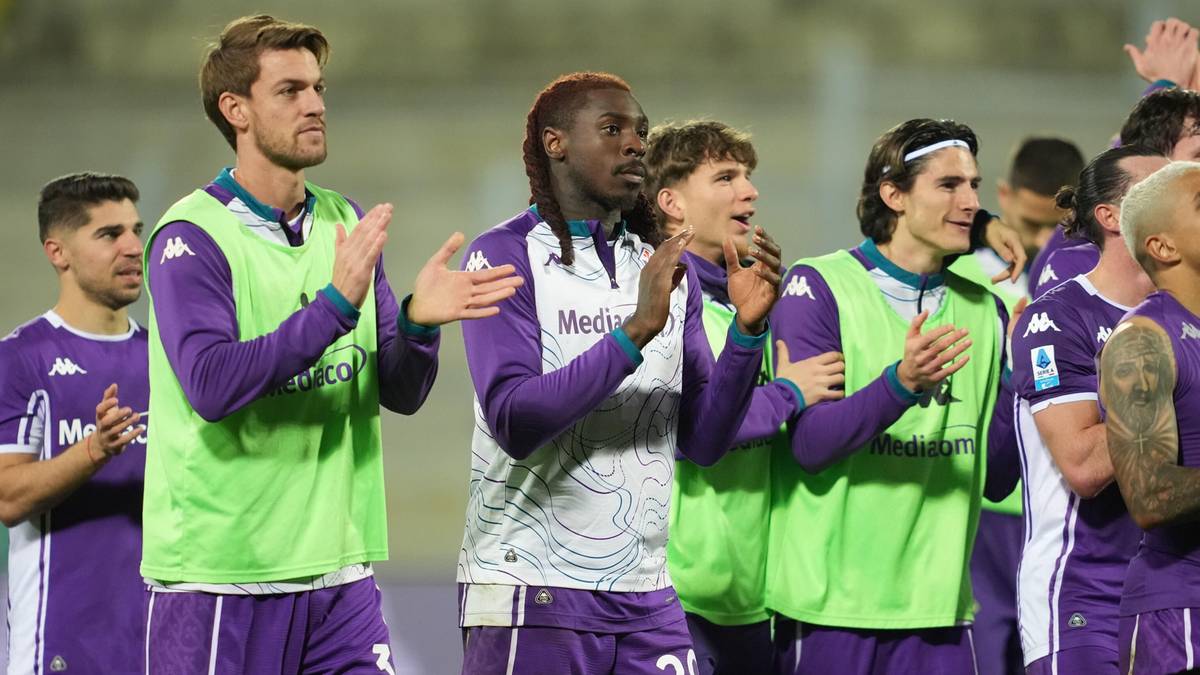 Piłkarze Fiorentiny klaszczą, ubrani w fioletowe stroje i zielone kamizelki treningowe.