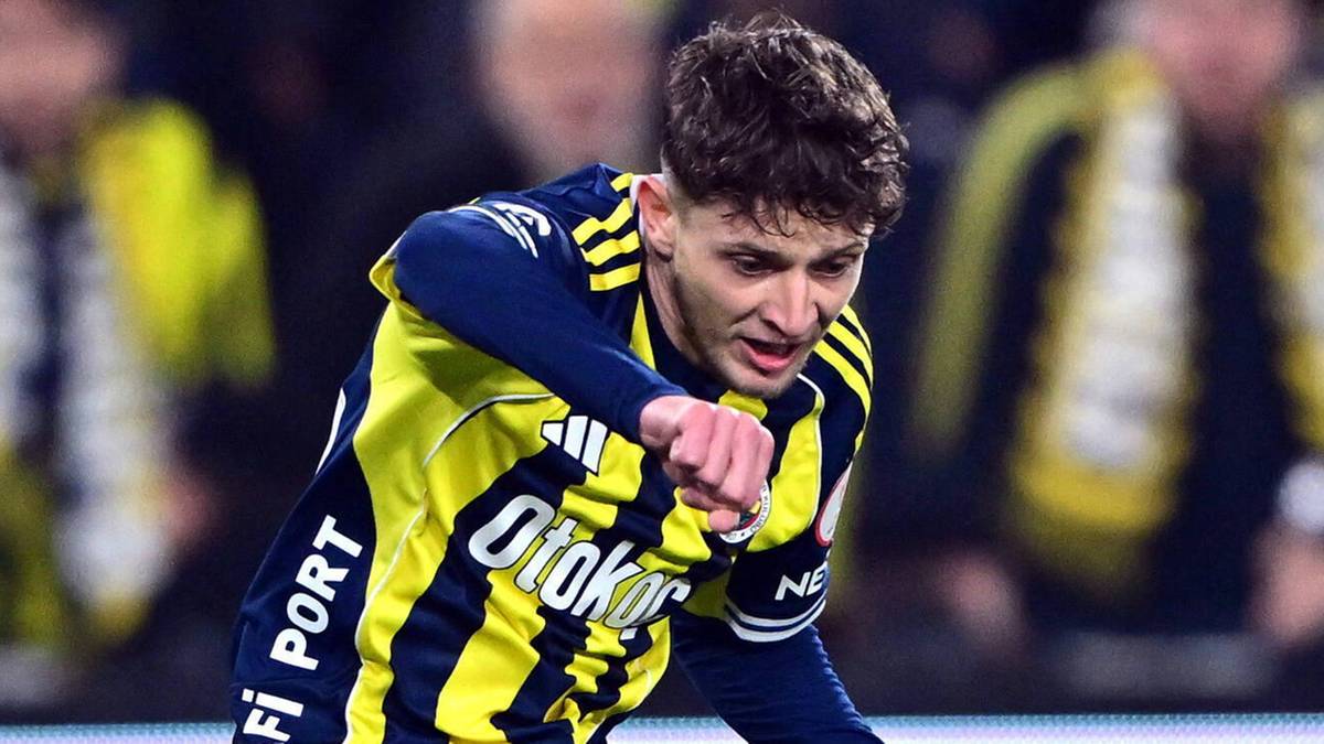 Piłkarz w stroju domowym Fenerbahce wykonuje strzał do piłki.