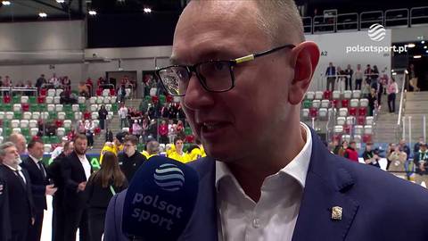 Mężczyzna w okularach i garniturze, prawdopodobnie trener, udziela wywiadu z mikrofonem Polsat Sport w tle.