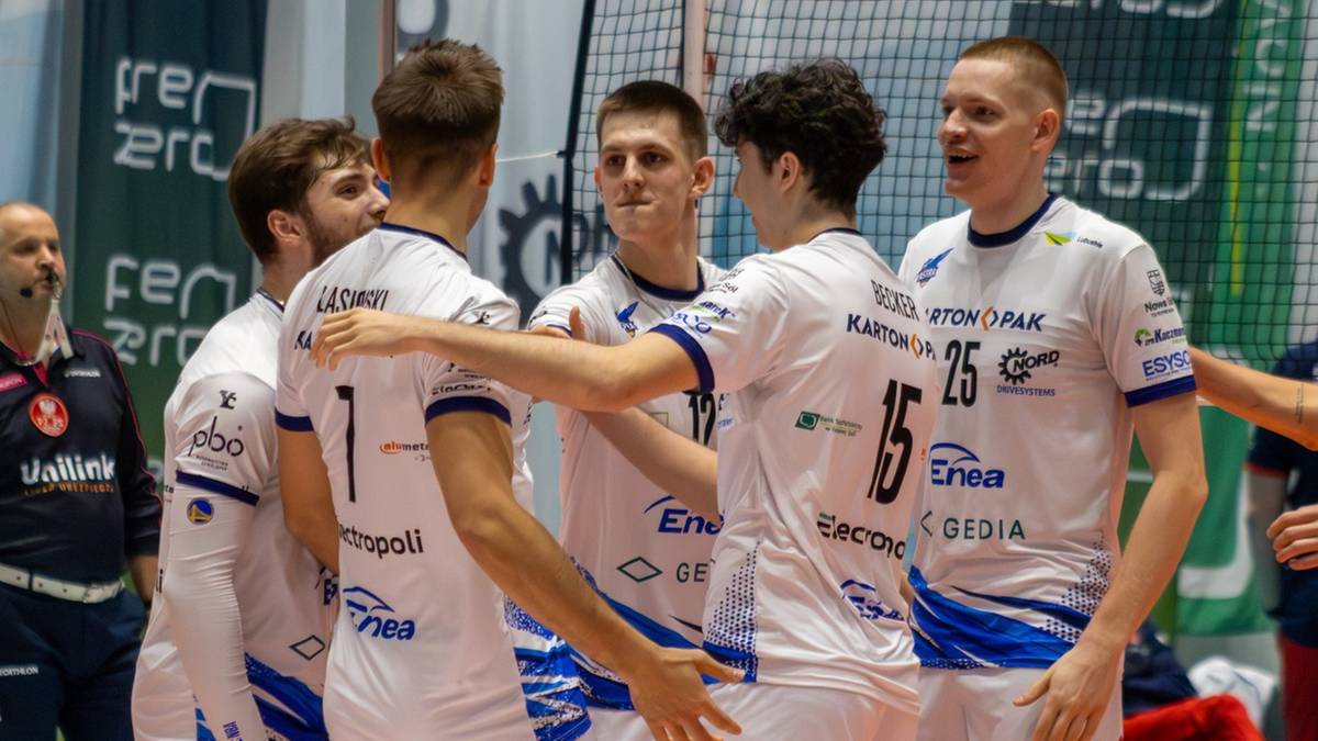 Siatkarze w białych strojach świętują na boisku.