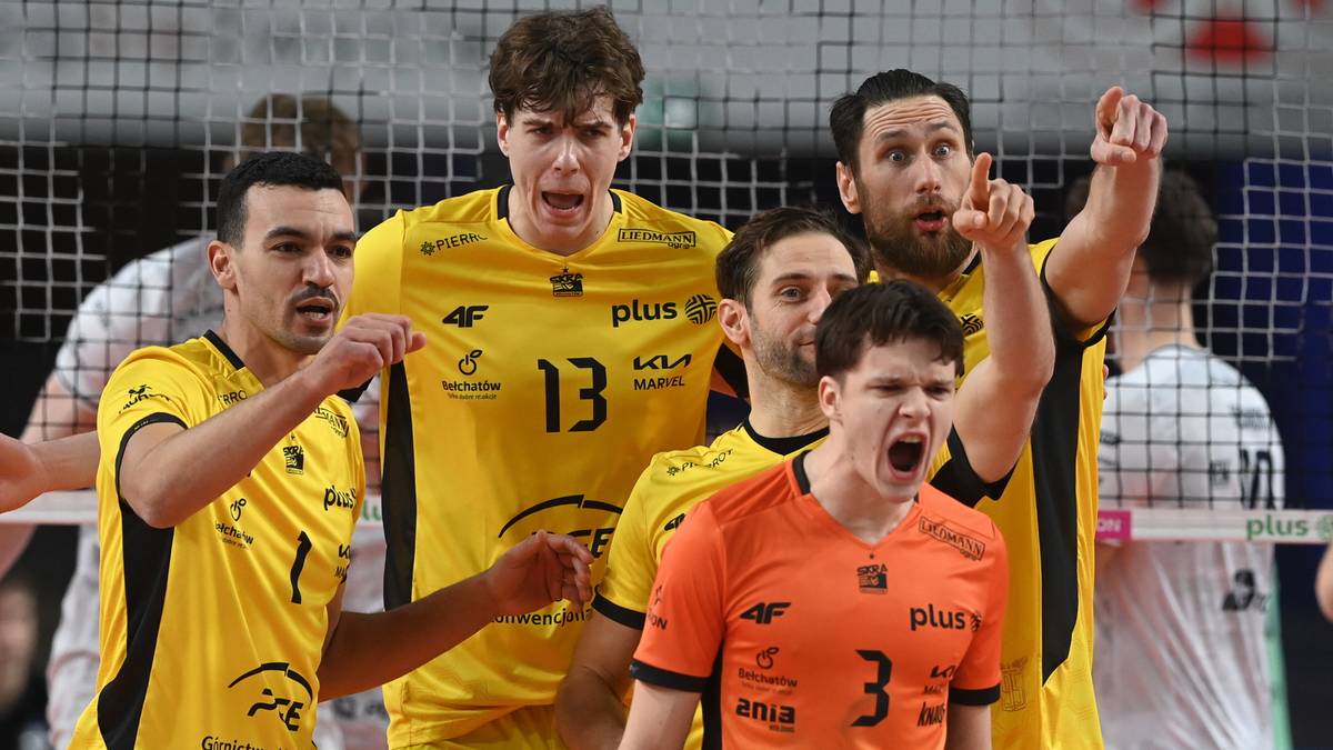 Grupa siatkarzy w ż&oacute;łtych i pomarańczowych strojach patrzą w tym samym kierunku, większość z nich krzyczy lub otwiera usta w geście okrzyku.