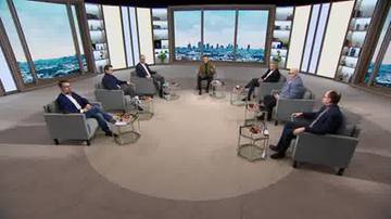 Grupa siedmiu mężczyzn w okręgu, siedzących na fotelach w studiu telewizyjnym.