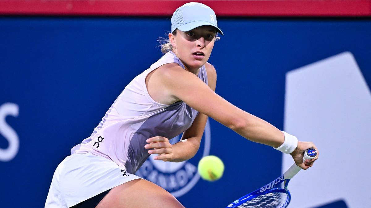 Iga Świątek podczas meczu tenisowego, uderzająca piłkę rakietą.