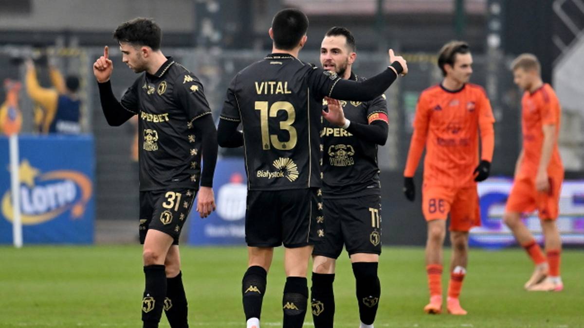 Piłkarze drużyny w czarnych strojach świętują zdobycie bramki, jeden z nich wskazuje palcem w górę.