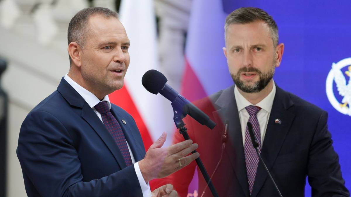 Dwóch mężczyzn w garniturach przemawia do mikrofonu, jeden z nich trzyma dłoń w geście podkreślającym wypowiedź, za nimi widnieje polska flaga.
