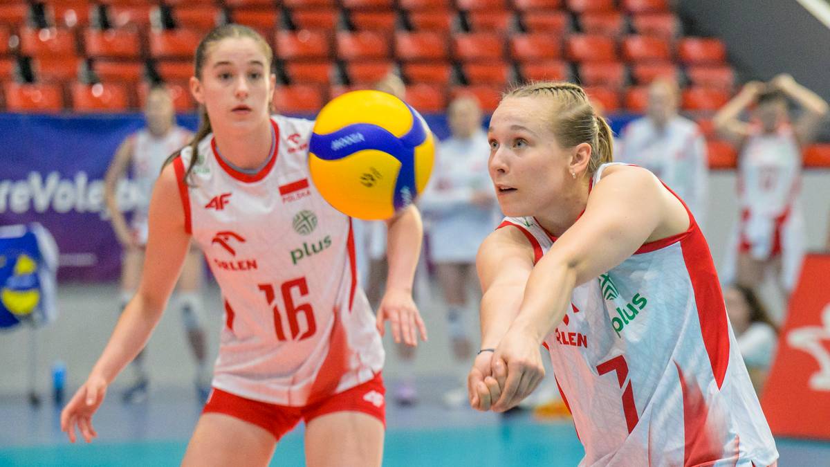 Dwie młode siatkarki w biało-czerwonych strojach z numerami 16 i 7 na plecach, podczas meczu. Jedna z nich po prawej stronie próbuje przyjąć piłkę, druga po lewej jest gotowa do dalszej akcji.