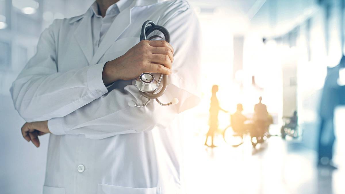 Lekarz trzymający stetoskop na tle rozmytego korytarza szpitalnego.