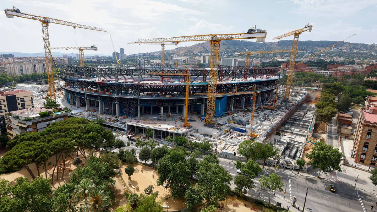 Widok z góry na stadion Camp Nou w Barcelonie podczas trwającej przebudowy. Widać konstrukcję obiektu, liczne żurawie budowlane oraz otaczające go tereny zielone i miejskie.