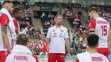 Siatkarze reprezentacji Polski w strojach biało-czerwonych, otoczeni przez trenera, dyskutują podczas meczu.
