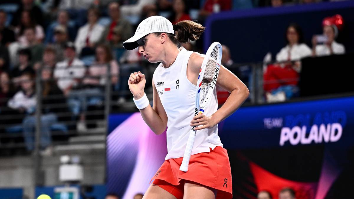 Tenisistka w białej czapce i białej koszulce z kr&oacute;tkim rękawem, w pomarańczowej sp&oacute;dniczce i białych butach, z rakietą w ręku, świętuje zwycięstwo na korcie.