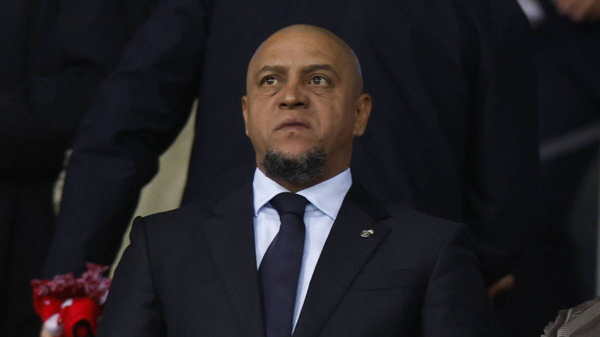 Grupa mężczyzn w garniturach siedząca w loży na trybunach podczas meczu.