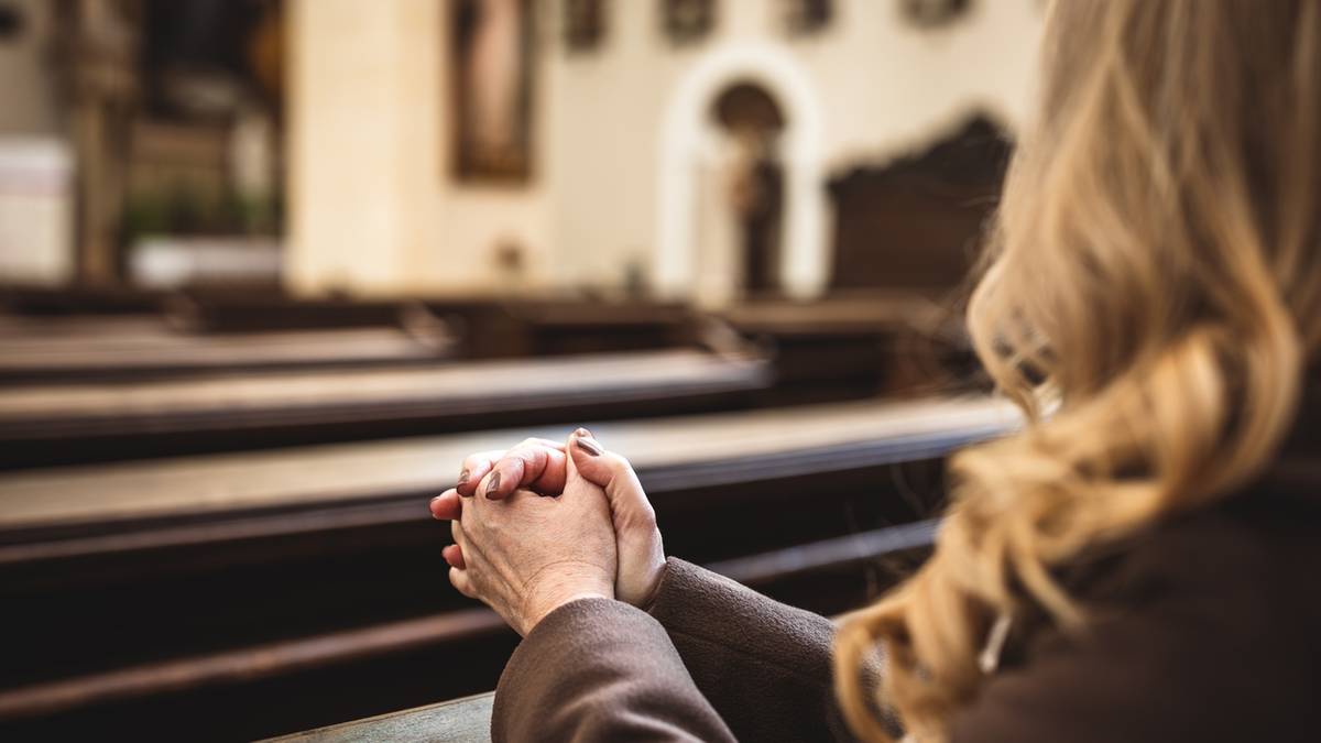 Dłoń kobiety złożone do modlitwy w kościele.
