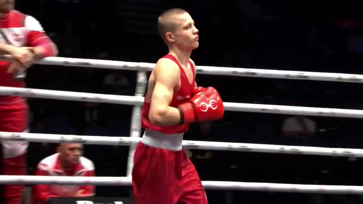 Młody bokser w czerwonym stroju i rękawicach na ringu.