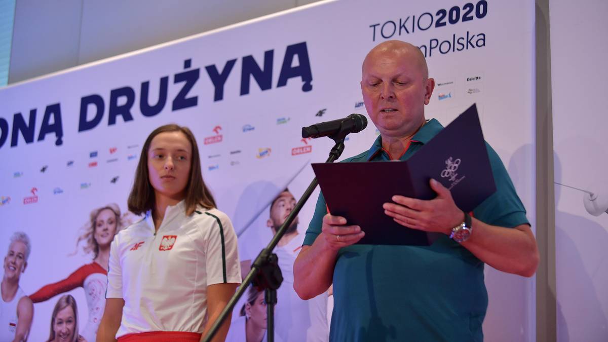 Mężczyzna przemawia, obok niego kobieta w stroju sportowym, na tle tablicy z napisem "TOKIO 2020 Polska" i zdjęciami sportowc&oacute;w.