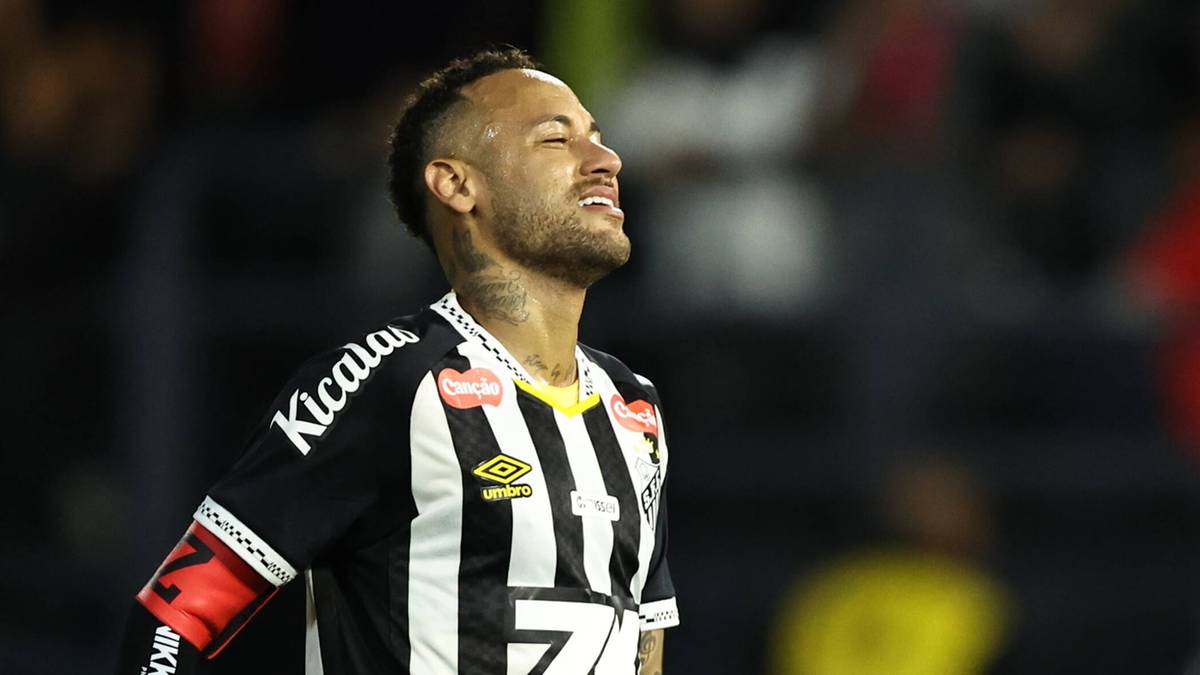 Piłkarz Neymar w czarno-białej koszulce Santosu, z zamkniętymi oczami i uśmiechem, na tle trybun.