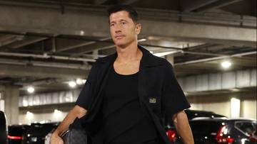 Robert Lewandowski w czarnej koszuli i podkoszulku, stojący w hali garażowej.