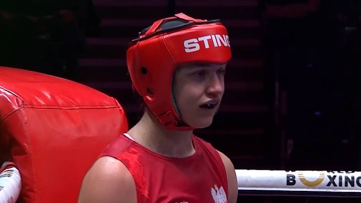 Zawodniczka boksu w kasku ochronnym w kolorze czerwonym, wpatrzona przed siebie.