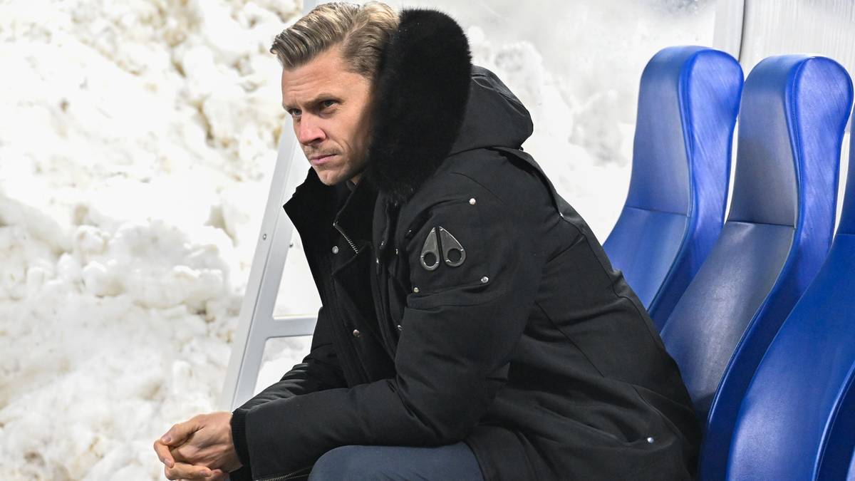 Mężczyzna w czarnej kurtce z kapturem siedzi na ławce.