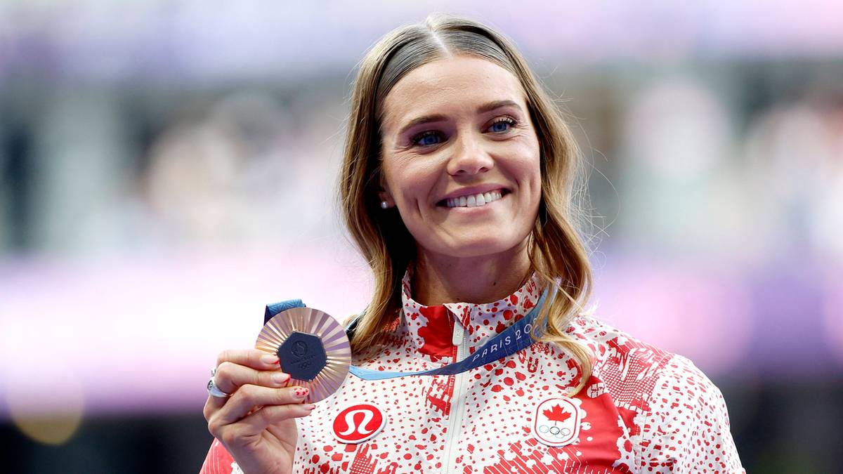 Uśmiechnięta lekkoatletka z Kanady w stroju sportowym trzyma w dłoni medal.