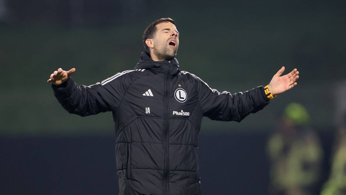 Trener Legii Warszawa w czarnej kurtce z uniesionymi rękami i zamkniętymi oczami.