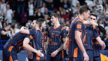 Siatkarze w strojach JSW Jastrzębski Węgiel świętują lub pocieszają się nawzajem na boisku, otoczeni przez kibiców na trybunach.