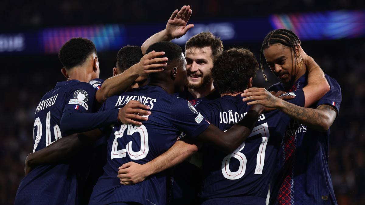 Grupa piłkarzy w niebieskich strojach świętuje zdobycie bramki, obejmując się nawzajem.