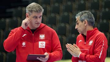 Dw&oacute;ch trener&oacute;w reprezentacji Polski w czerwonych bluzach rozmawia, jeden trzyma tablet.