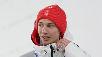 Skoczek narciarski Kacper Tomasiak w kurtce reprezentacji Polski z medalem olimpijskim na szyi.