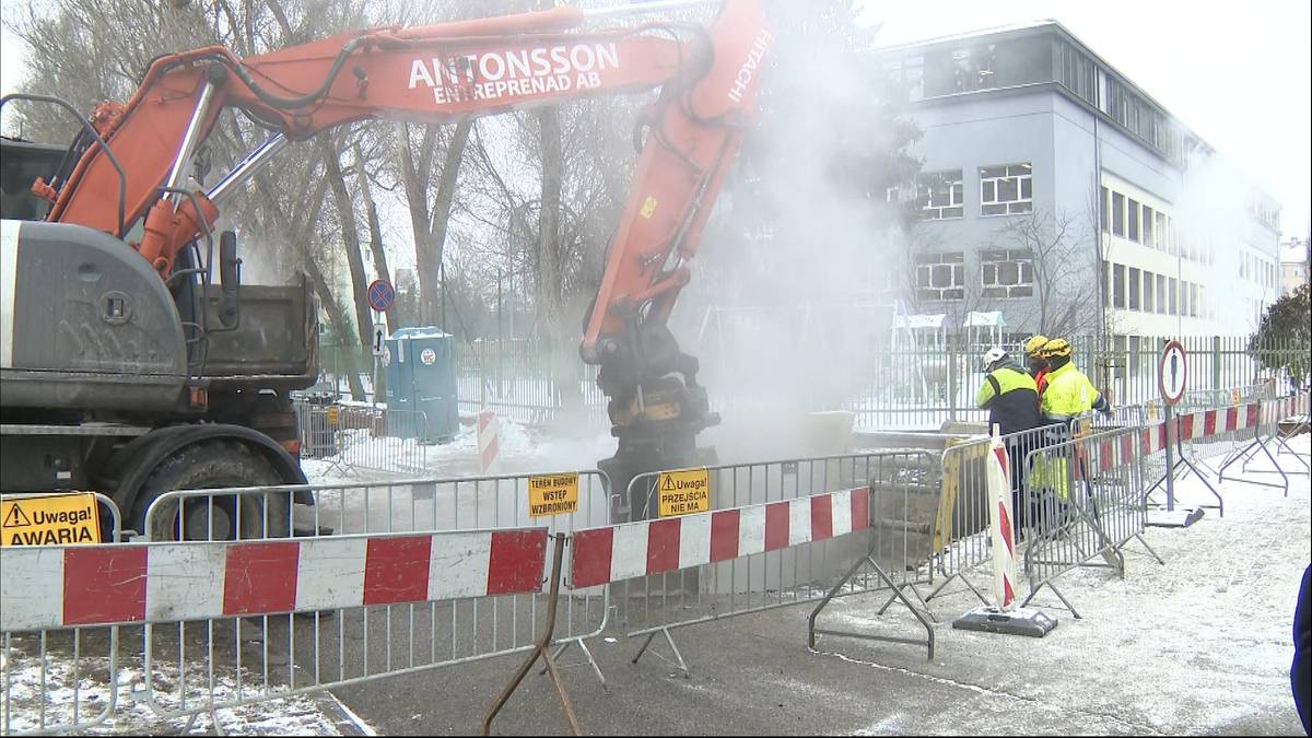 Koparka pracuje na ulicy, z maszyny wydobywa się para wodna.