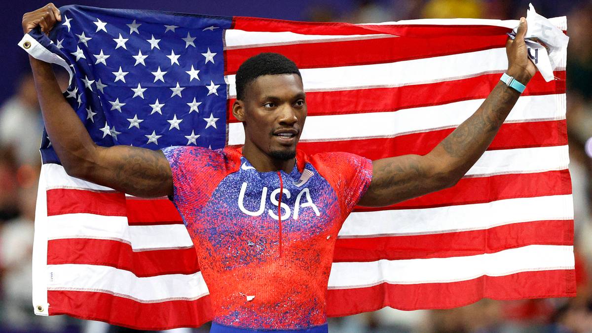 Uśmiechnięty amerykański sportowiec odnosi zwycięstwo, trzymając flagę USA za plecami.