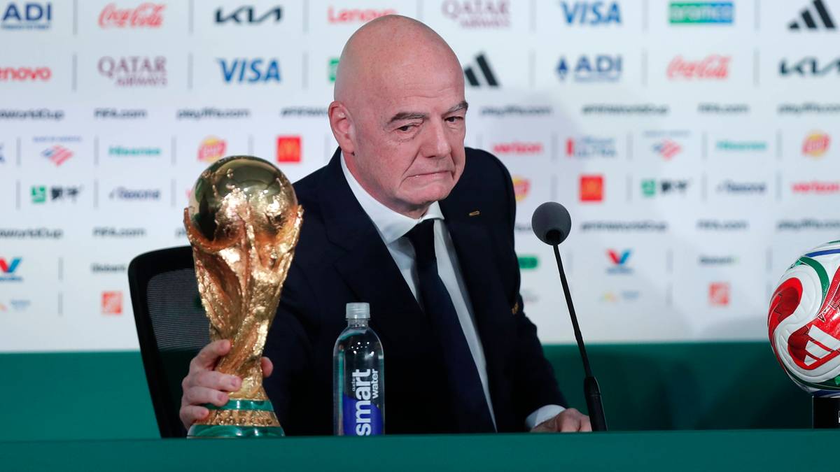 Gianni Infantino trzyma puchar Mistrzostw Świata podczas konferencji prasowej.