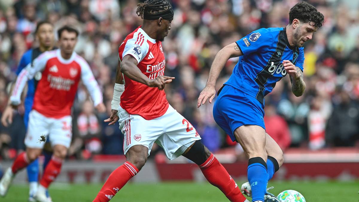 Dw&oacute;ch piłkarzy toczy walkę o piłkę na zielonym boisku podczas meczu piłki nożnej.