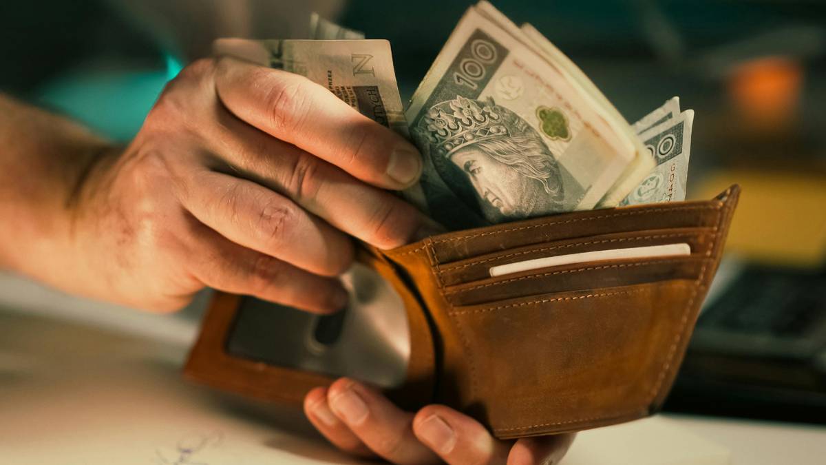 Dłoń przekłada banknoty z portfela.