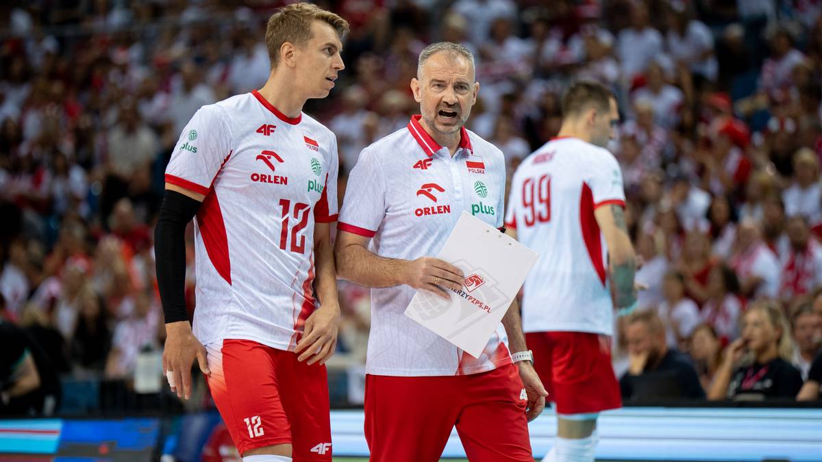 Trzech siatkarzy reprezentacji Polski w białych koszulkach z czerwonymi elementami i numerami 12, 99. Trener w białej koszulce z czerwonym kołnierzykiem i czapką, trzyma w rękach kartkę.