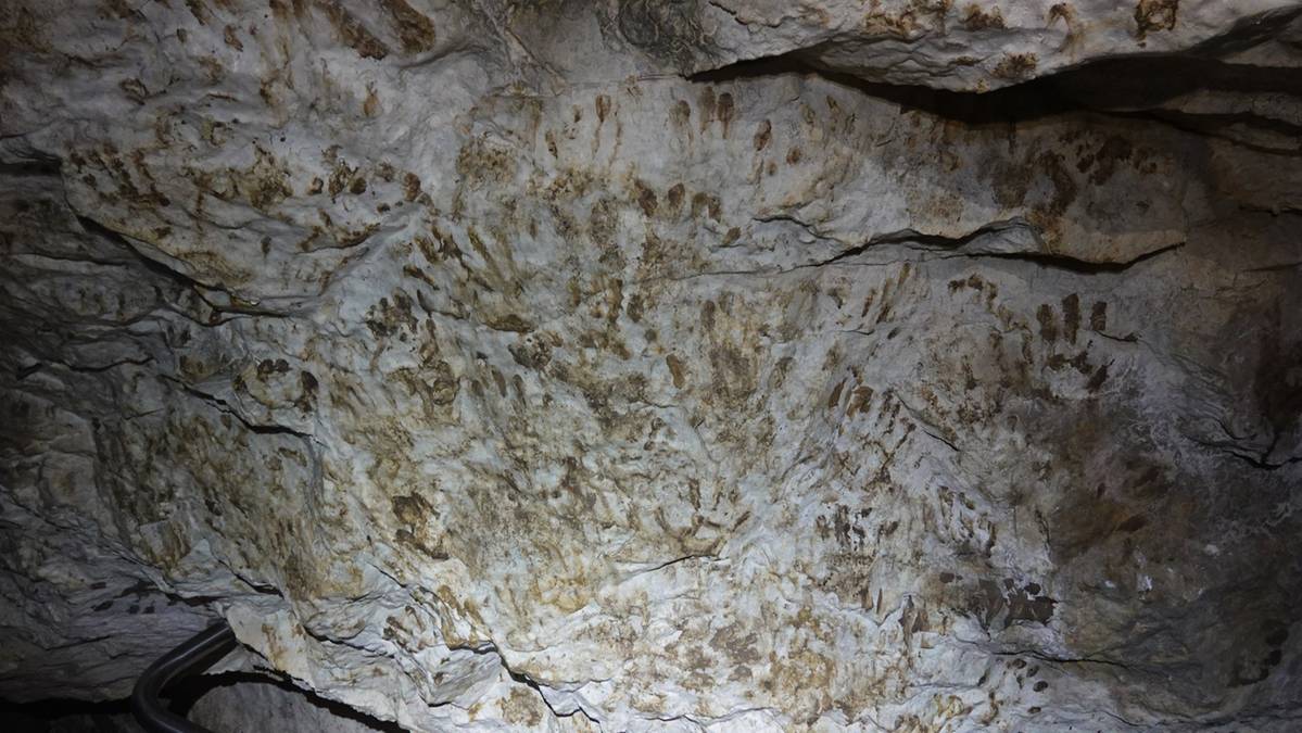 Ściany Jaskini Mroźnej pokryte licznymi śladami ludzkich dłoni i napisami wykonanymi błotem.