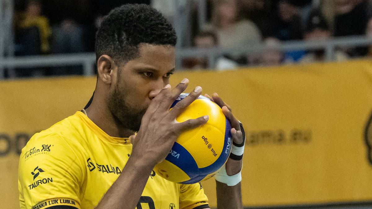 Siatkarz w ż&oacute;łtej koszulce z numerem 9 na piersi, trzymający piłkę siatkową przy twarzy.