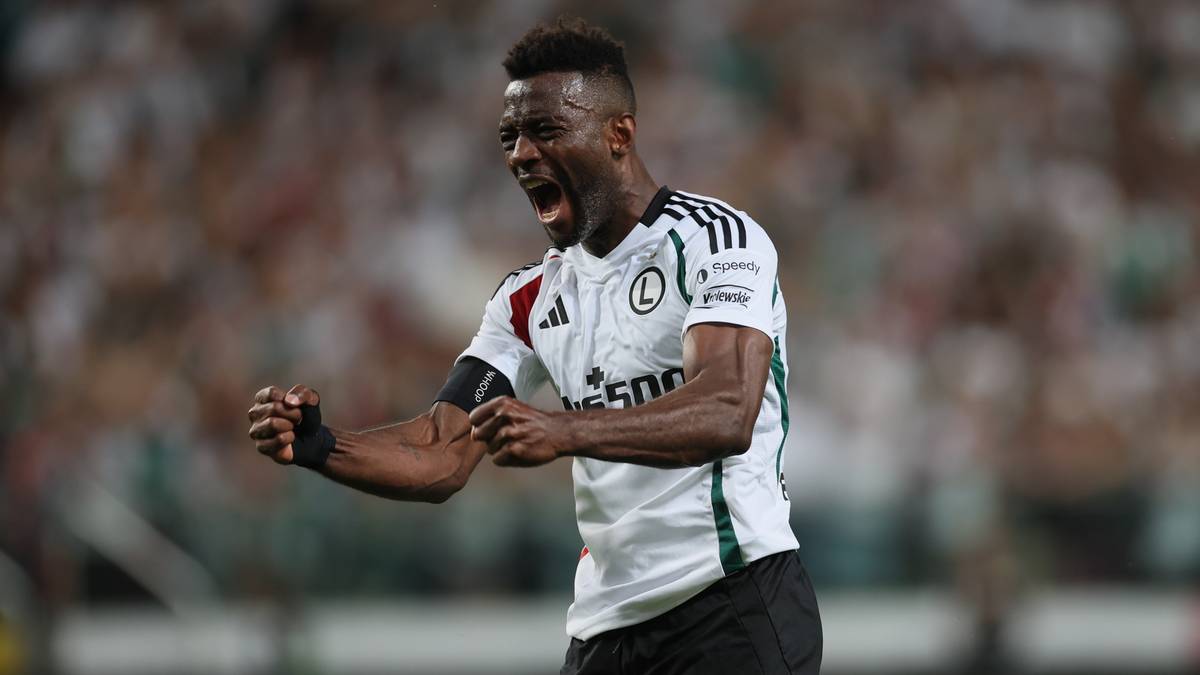 Piłkarz w białej koszulce Legii Warszawa świętuje radośnie.