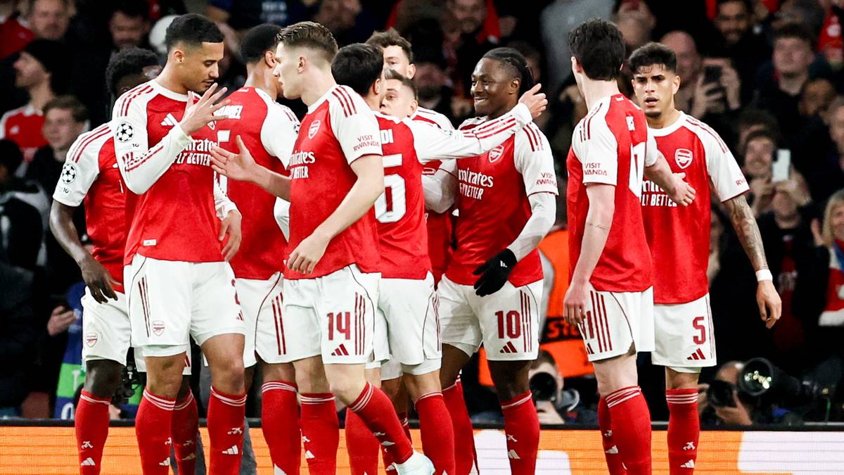 Piłkarze Arsenalu w czerwonych strojach piłkarskich świętują razem na boisku.