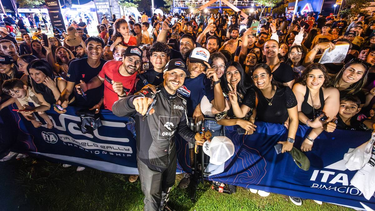 Kajetan Kajetanowicz i Jarosław Szczepaniak pozują do zdjęcia na mecie rajdu, otoczeni przez wiwatujący tłum kibiców.