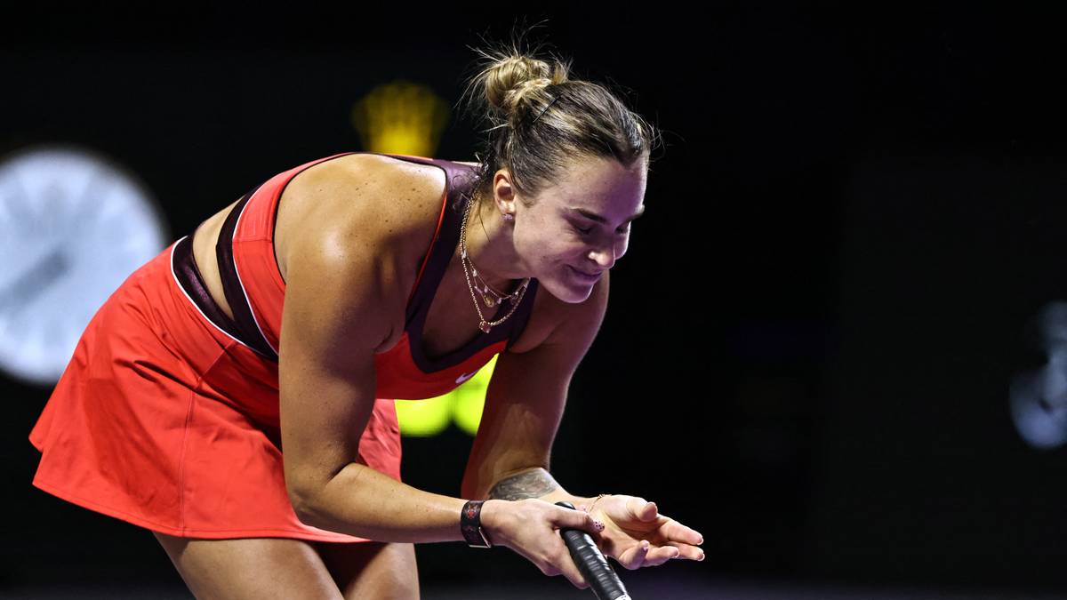 Tenisistka Aryna Sabalenka pochyla się nad rakietą tenisową