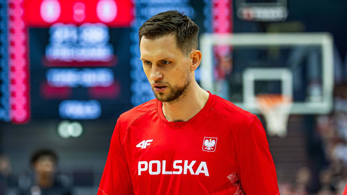 Portret mężczyzny w czerwonej koszulce reprezentacji Polski w koszykówce.